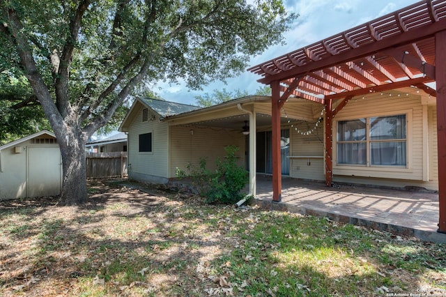 back of house featuring an outbuilding, a patio, fence, a ceiling fan, and a pergola