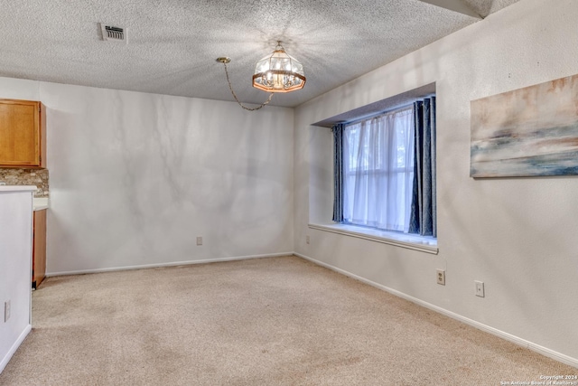 spare room with light carpet, baseboards, visible vents, and a textured ceiling