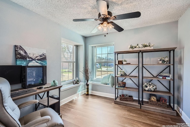 home office featuring a ceiling fan, a textured ceiling, baseboards, and wood finished floors