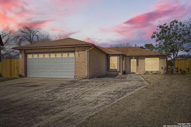 ranch-style home with brick siding, a shingled roof, fence, a garage, and driveway