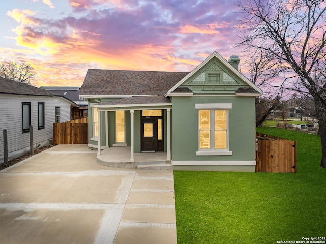 view of front of house featuring roof with shingles, a lawn, a chimney, and fence