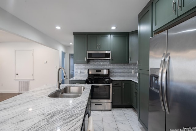 kitchen featuring light stone counters, stainless steel appliances, visible vents, decorative backsplash, and a sink