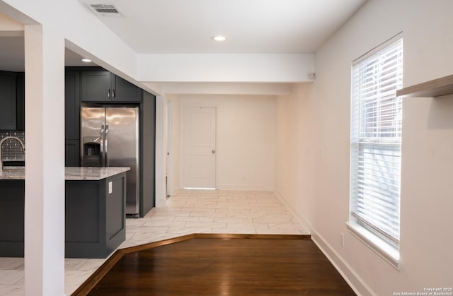 kitchen with visible vents, light stone countertops, marble finish floor, stainless steel refrigerator with ice dispenser, and a sink