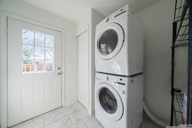 laundry room with baseboards, marble finish floor, laundry area, and stacked washer / drying machine