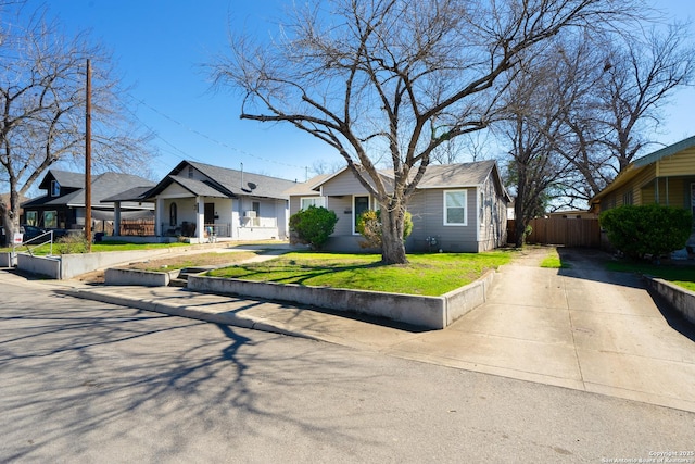 view of front facade featuring a front yard, driveway, and fence