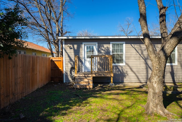 rear view of property featuring a yard and fence