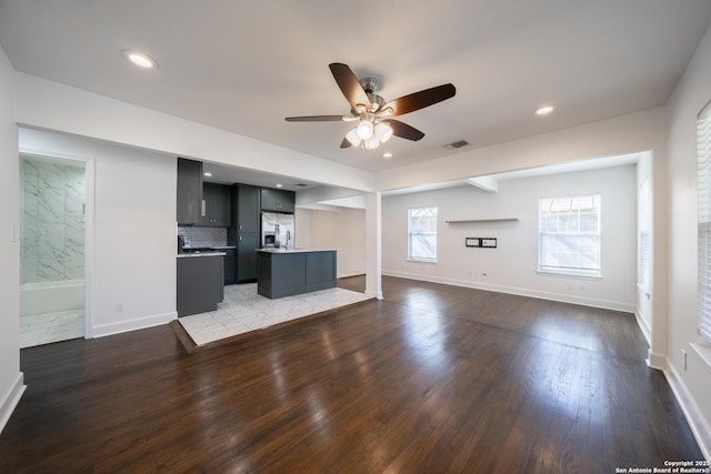 unfurnished living room featuring a ceiling fan, baseboards, visible vents, and wood finished floors