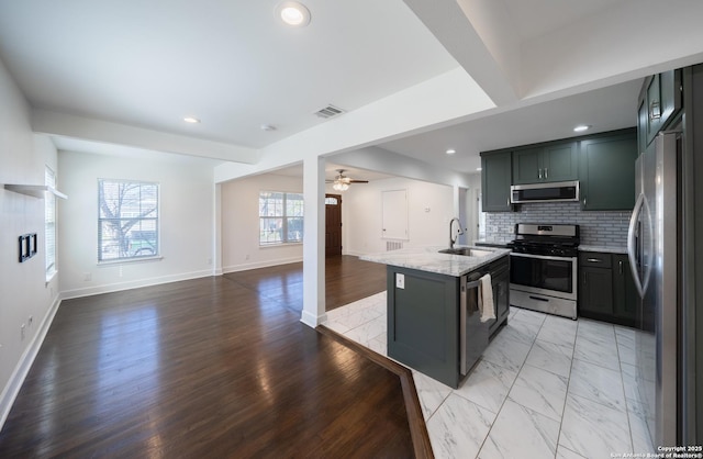 kitchen featuring stainless steel appliances, tasteful backsplash, visible vents, open floor plan, and a sink