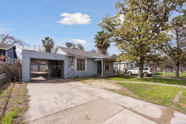 view of front of home featuring a carport, concrete driveway, fence, and a front lawn