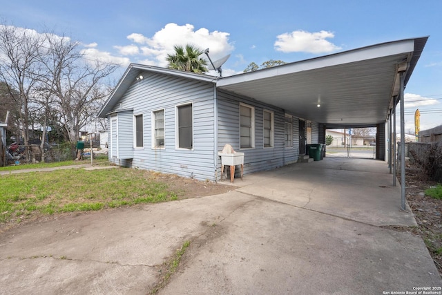 view of side of home with driveway, fence, an attached carport, and a lawn