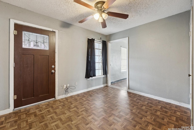 foyer entrance featuring ceiling fan, baseboards, and a textured ceiling