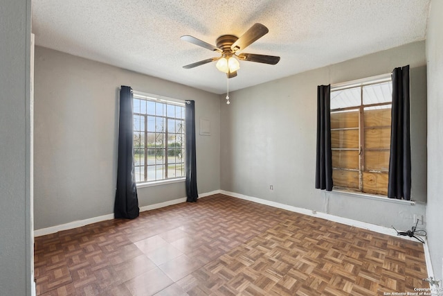 empty room with ceiling fan, baseboards, and a textured ceiling