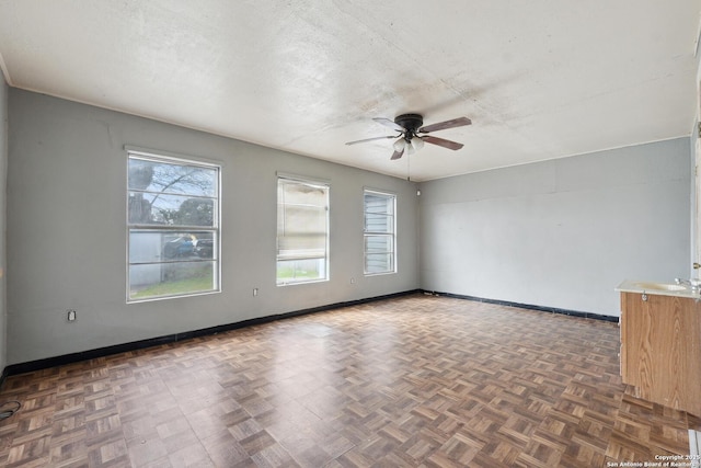 unfurnished room featuring ceiling fan, baseboards, and a textured ceiling