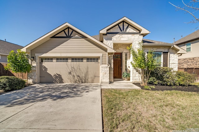 view of front of property with driveway, stone siding, an attached garage, fence, and a front yard