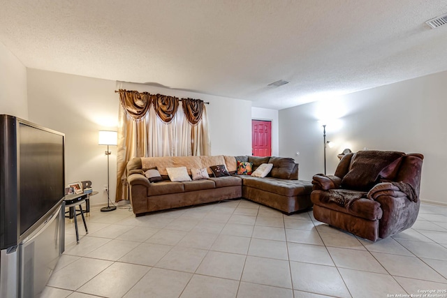 living room with a textured ceiling, light tile patterned floors, and visible vents