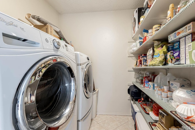 washroom with washer and dryer, laundry area, a textured ceiling, and light tile patterned floors