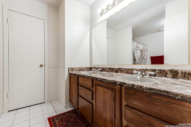 full bath with a textured ceiling, double vanity, a sink, and tile patterned flooring