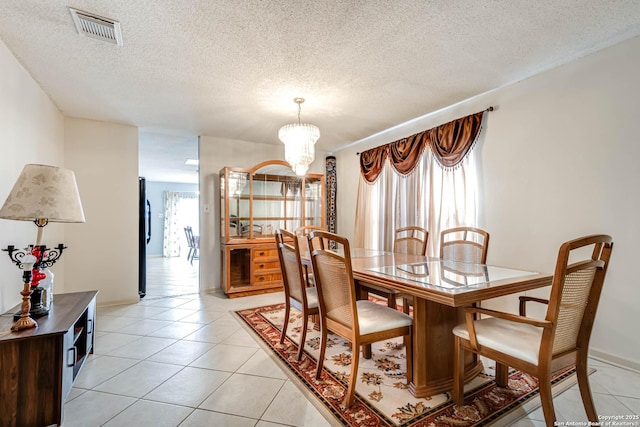 dining space with a chandelier, visible vents, a textured ceiling, and light tile patterned floors