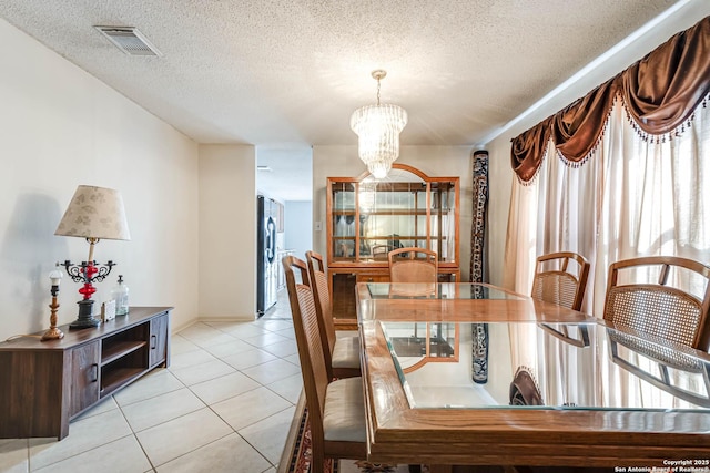 dining area featuring a chandelier, light tile patterned floors, a textured ceiling, and visible vents