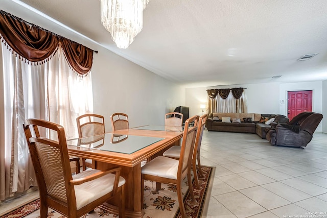 dining room with a textured ceiling, light tile patterned flooring, visible vents, and an inviting chandelier