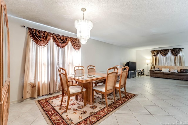 dining area with a chandelier, light tile patterned flooring, and a textured ceiling