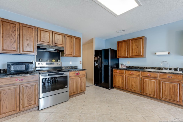 kitchen with visible vents, brown cabinetry, a sink, under cabinet range hood, and black appliances