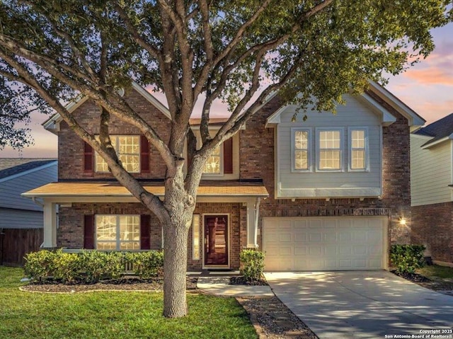 traditional-style home with a garage, brick siding, driveway, and fence