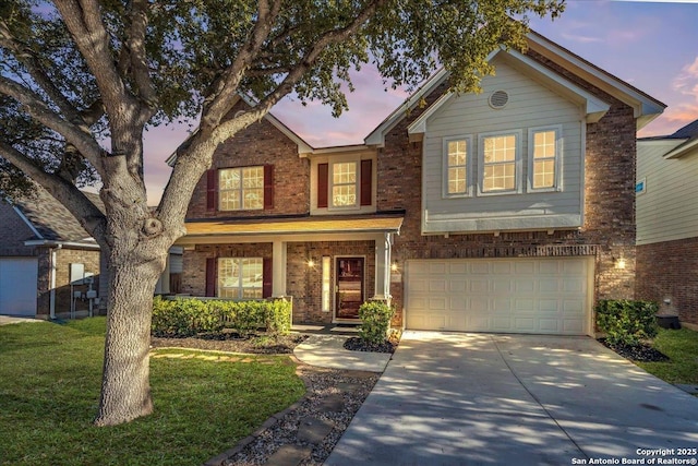 traditional-style home with driveway, an attached garage, a front yard, and brick siding