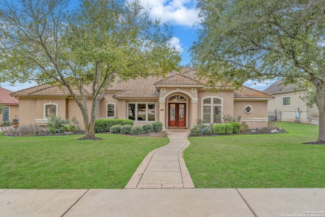 mediterranean / spanish-style house featuring a tiled roof, a front yard, fence, and stucco siding