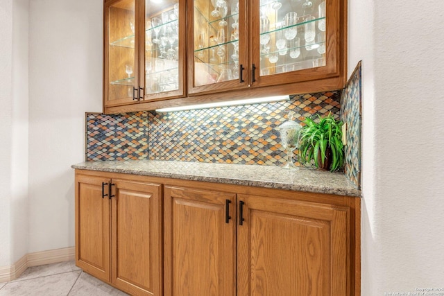 bar with light tile patterned floors, tasteful backsplash, and baseboards