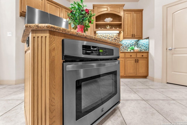 kitchen featuring light stone countertops, light tile patterned floors, decorative backsplash, and oven