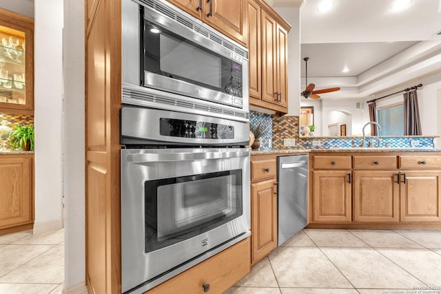 kitchen with light tile patterned floors, stainless steel appliances, tasteful backsplash, and ceiling fan