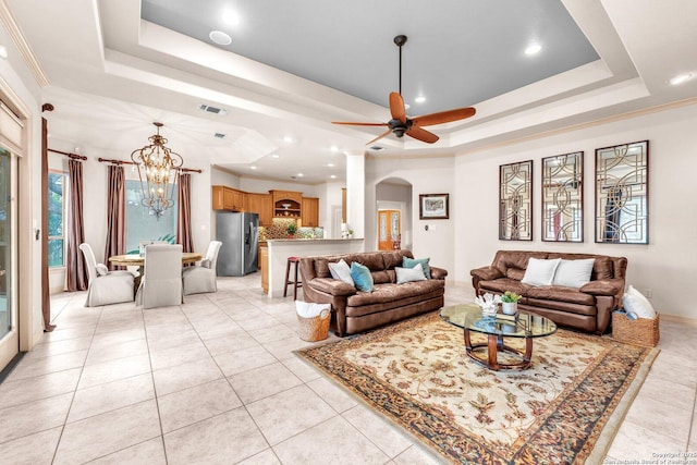 living area with visible vents, arched walkways, a raised ceiling, ceiling fan with notable chandelier, and light tile patterned flooring