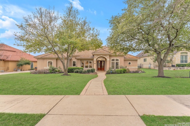 view of front of house with a front lawn, a tile roof, and stucco siding