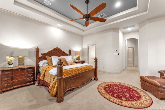 carpeted bedroom featuring arched walkways, a raised ceiling, and visible vents