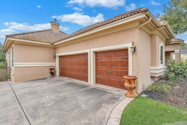 view of property exterior featuring a garage, a tile roof, concrete driveway, stucco siding, and a chimney