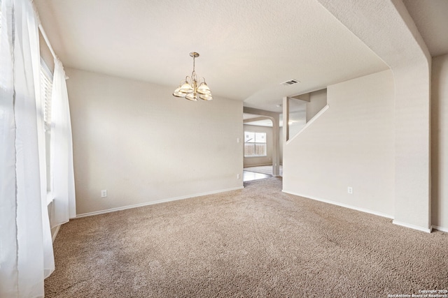 spare room with a textured ceiling, a notable chandelier, carpet flooring, visible vents, and stairs