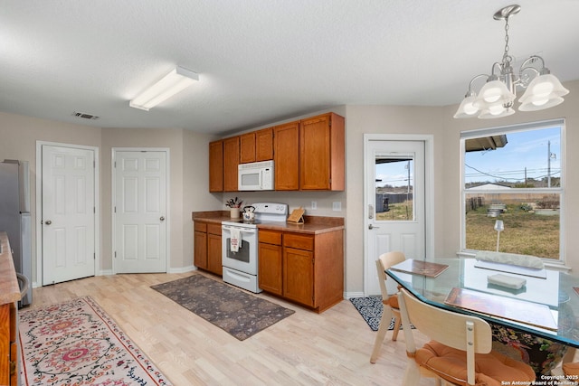 kitchen featuring light wood finished floors, white appliances, visible vents, and brown cabinets