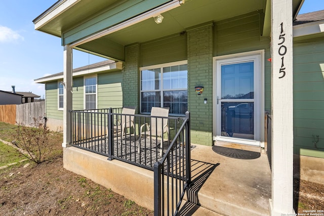 view of exterior entry with a porch and brick siding