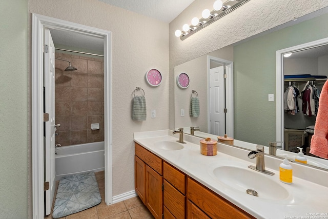 full bathroom featuring double vanity, tile patterned flooring, a walk in closet, and a sink