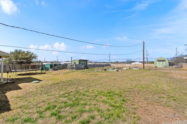 view of yard featuring a trampoline and fence