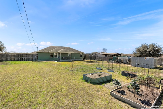 view of yard featuring a trampoline, fence private yard, and a vegetable garden