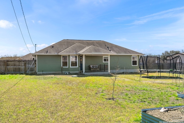 back of property featuring a trampoline, fence, a patio, and a yard