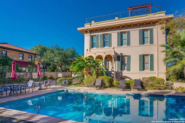 back of house featuring a patio, fence, a fenced in pool, and stucco siding