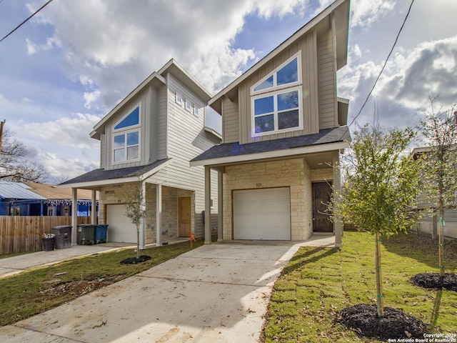 view of front of house with concrete driveway, stone siding, an attached garage, fence, and a front yard