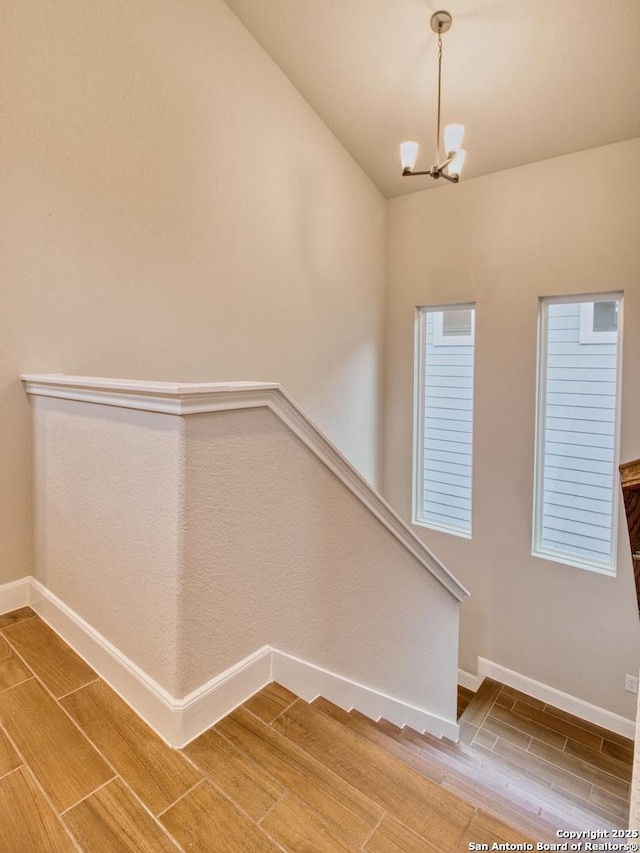 staircase featuring a notable chandelier, baseboards, and wood tiled floor