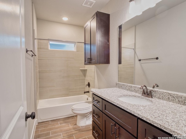 bathroom featuring wood finish floors, visible vents, toilet, tub / shower combination, and vanity