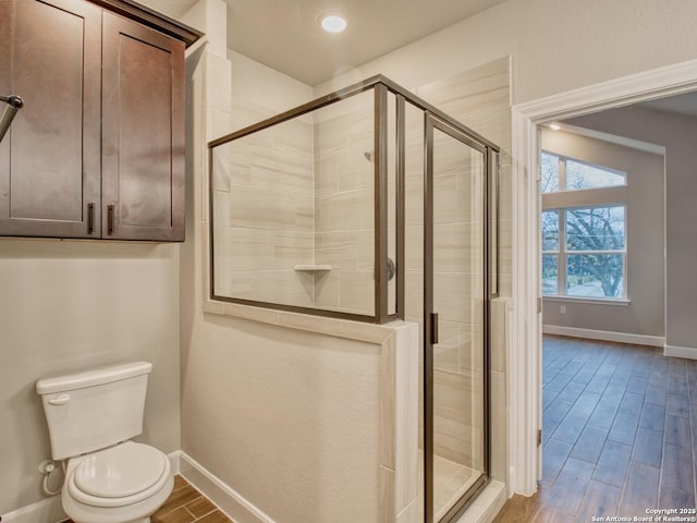 bathroom featuring wood finish floors, a shower stall, toilet, and baseboards