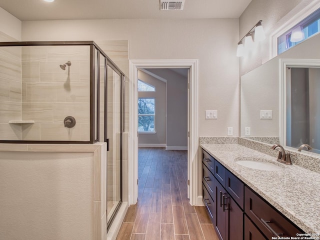 full bath with visible vents, a shower stall, vanity, and wood finished floors