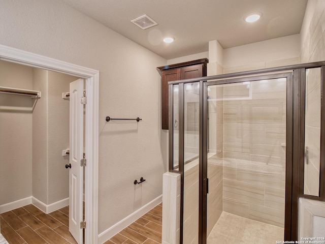 full bath featuring a stall shower, wood tiled floor, visible vents, and baseboards